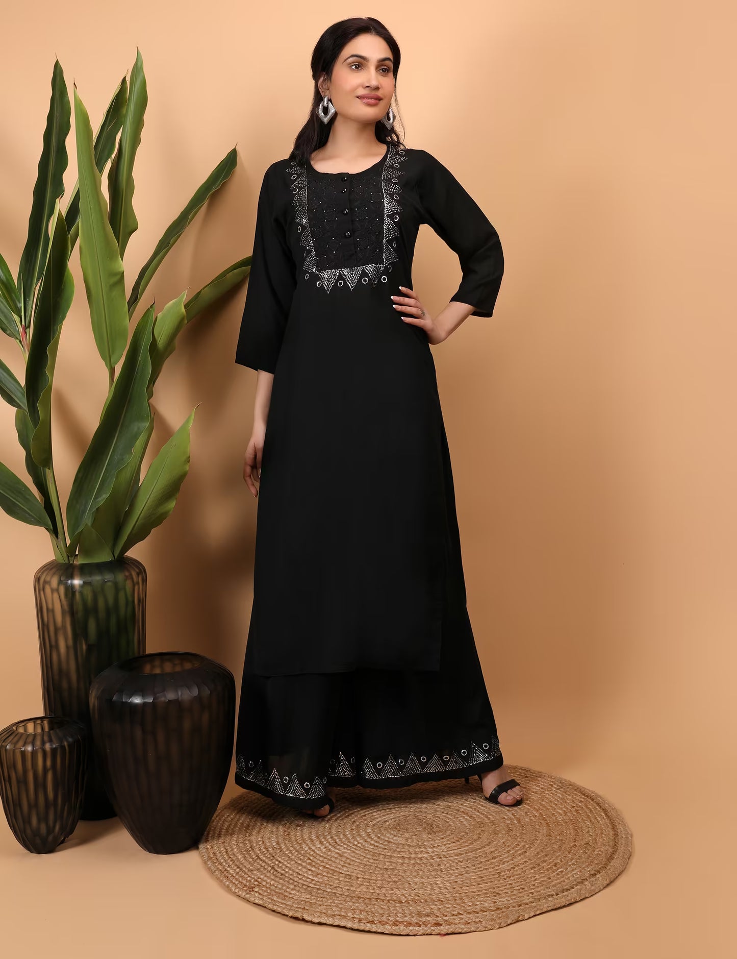 Woman wearing a black Kurti Plazzo Shrug Set with lace details standing against a beige background