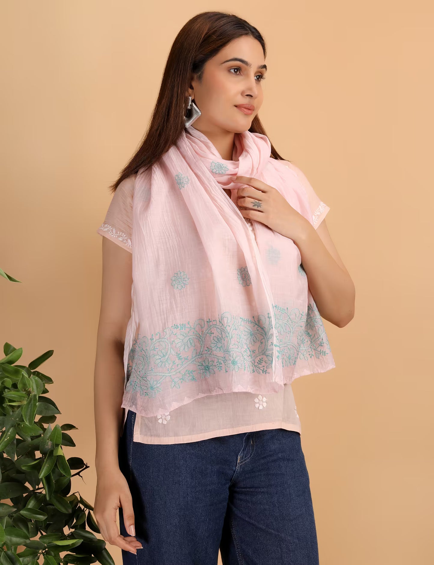 Woman wearing a pink scarf with blue Chikankari patterns against a beige background