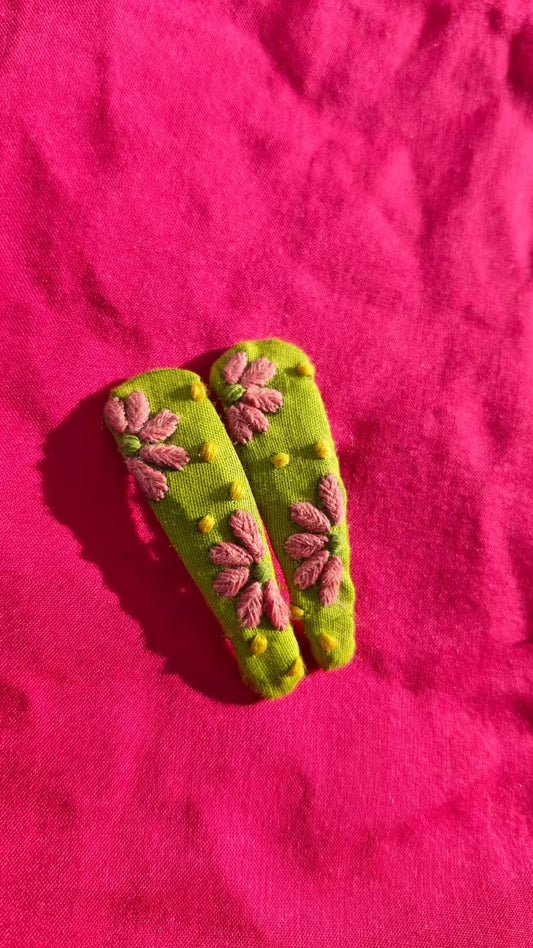Green hair clip with floral design on a pink background