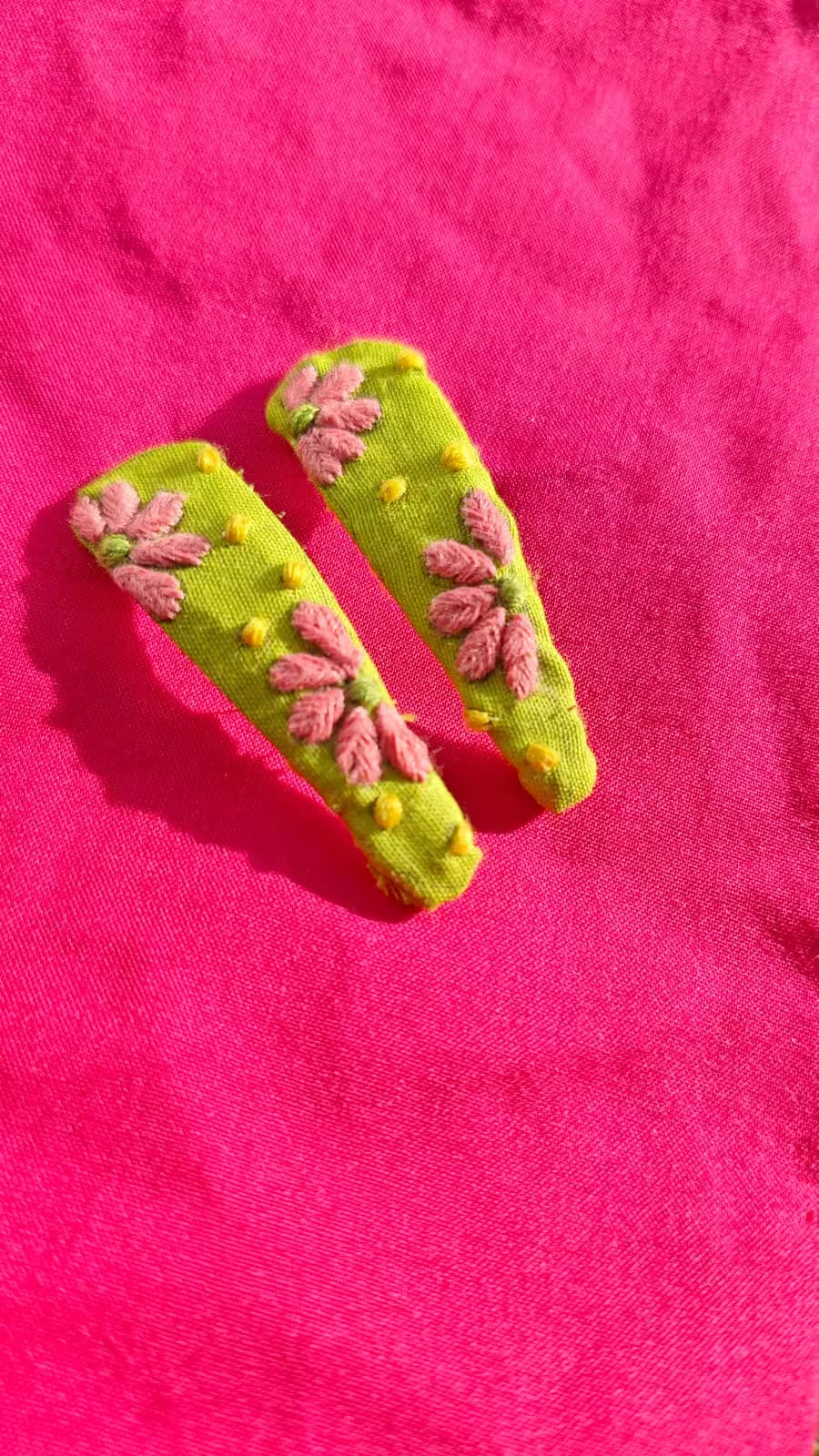 Green hair clips with floral designs on a pink background