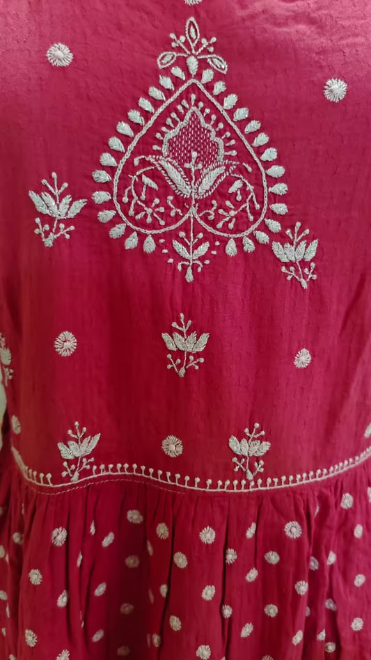 Red dress with white Chikankari patterns on a close-up view