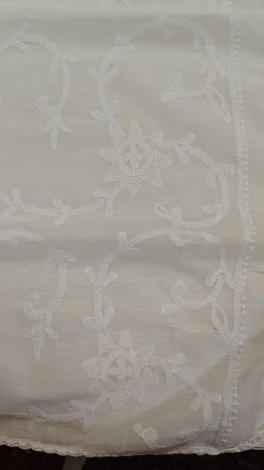 White lace fabric with intricate Chikankari patterns on a plain background