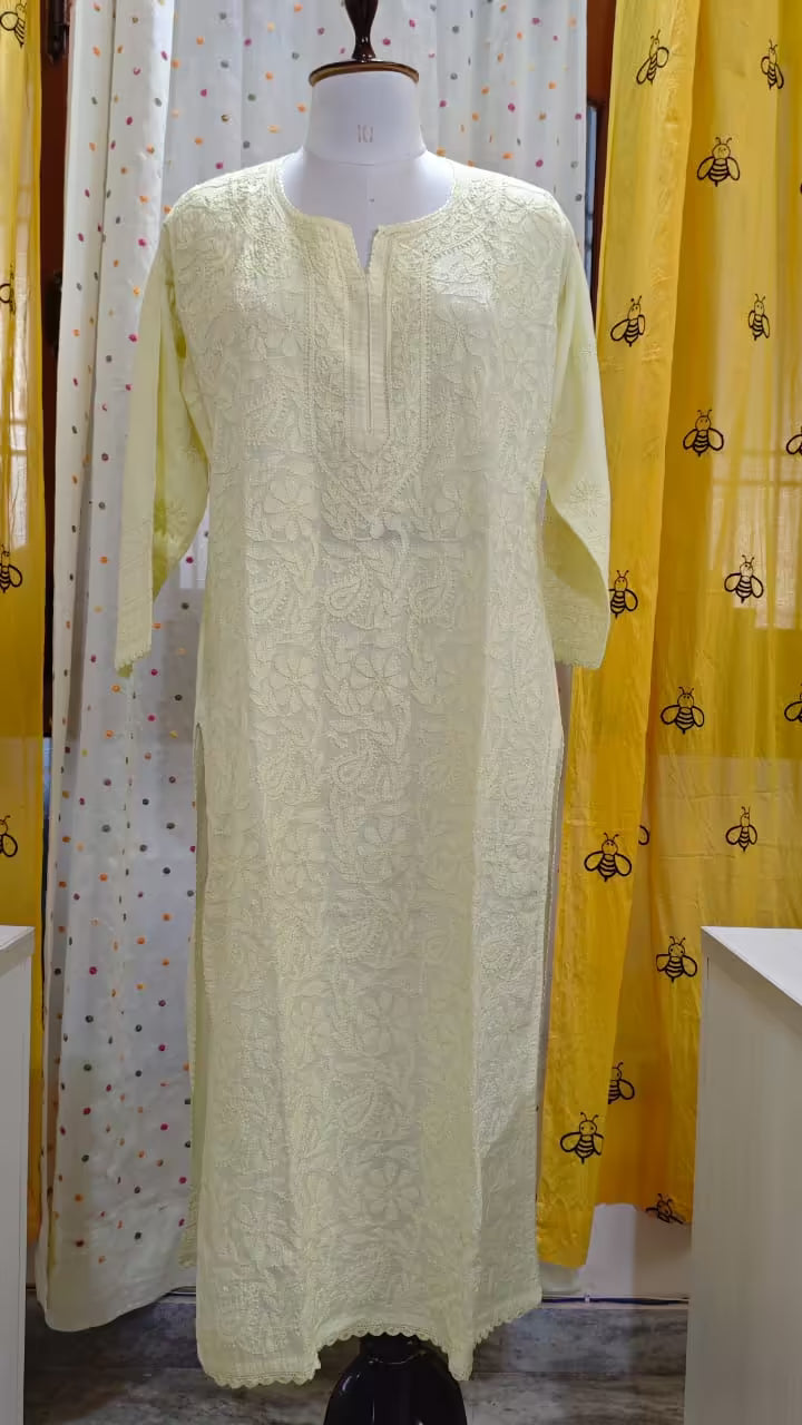 Mannequin wearing a light-colored embroidered Chikankari dress against a patterned curtain background