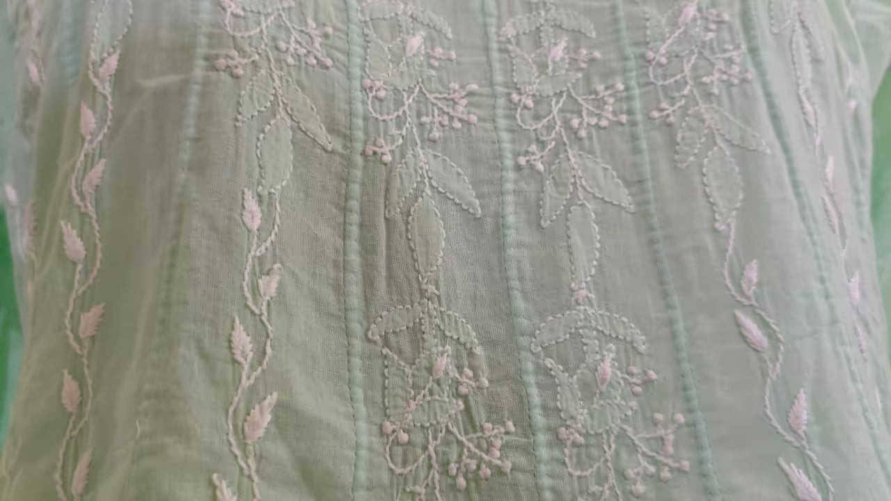 Close-up of a green fabric with intricate pink Chikankari embroidery