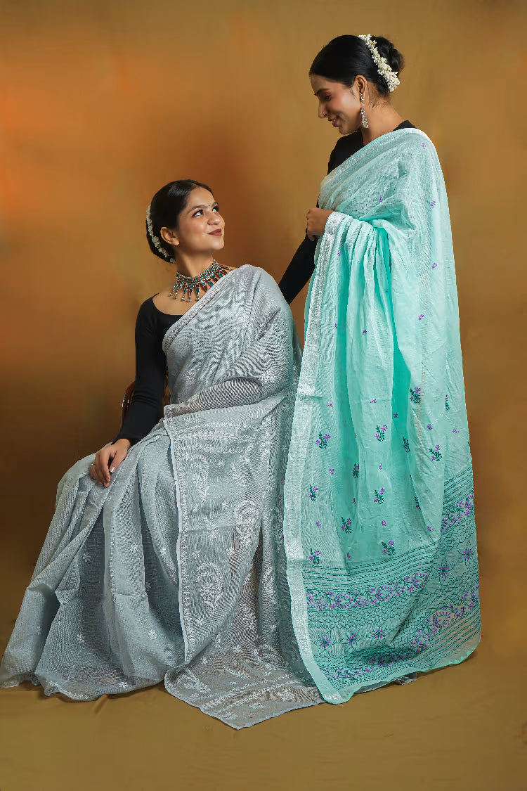 Two women wearing sarees against a warm-toned background