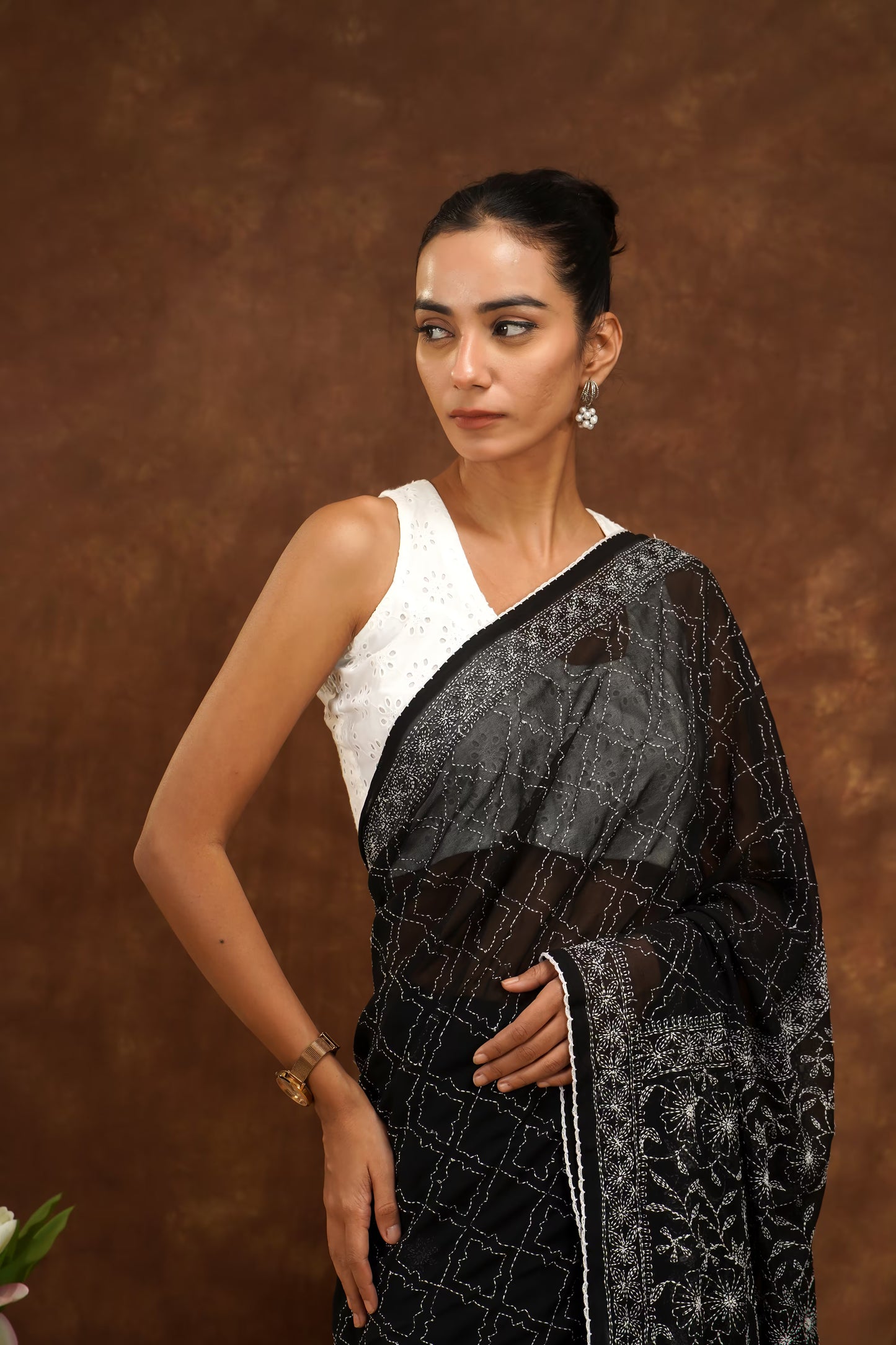 Woman wearing a black and white saree against a brown background