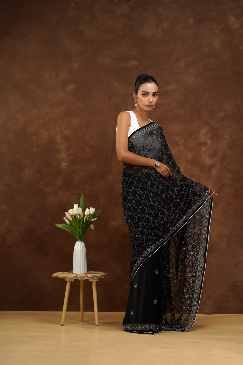 Woman in a black saree with white blouse against a brown background
