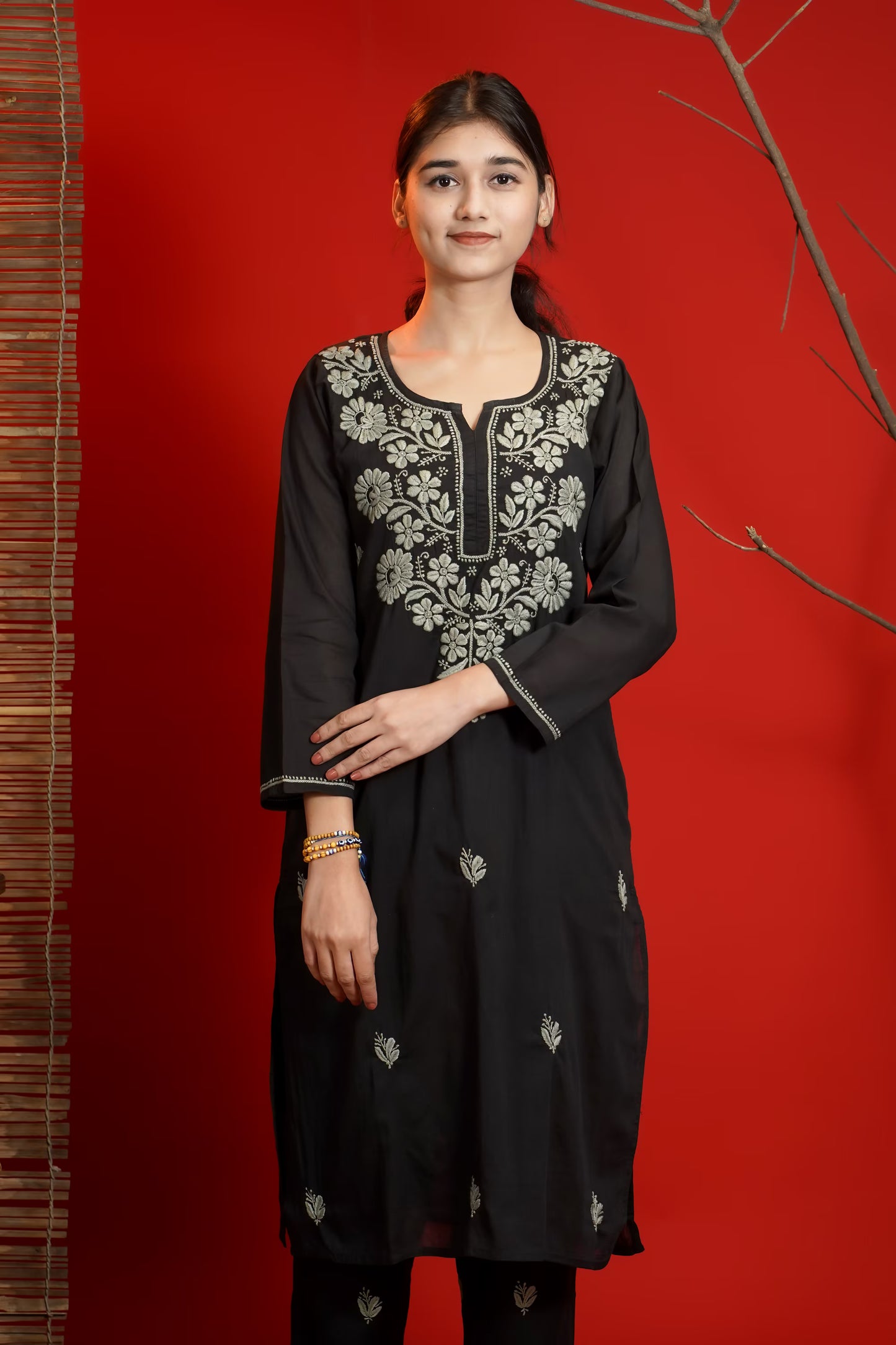 Woman wearing a black embroidered kurta against a red background