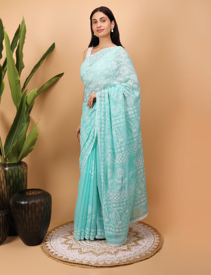 Woman wearing a light blue  Chikankari saree with white  Hand Embroidered patterns on a beige background