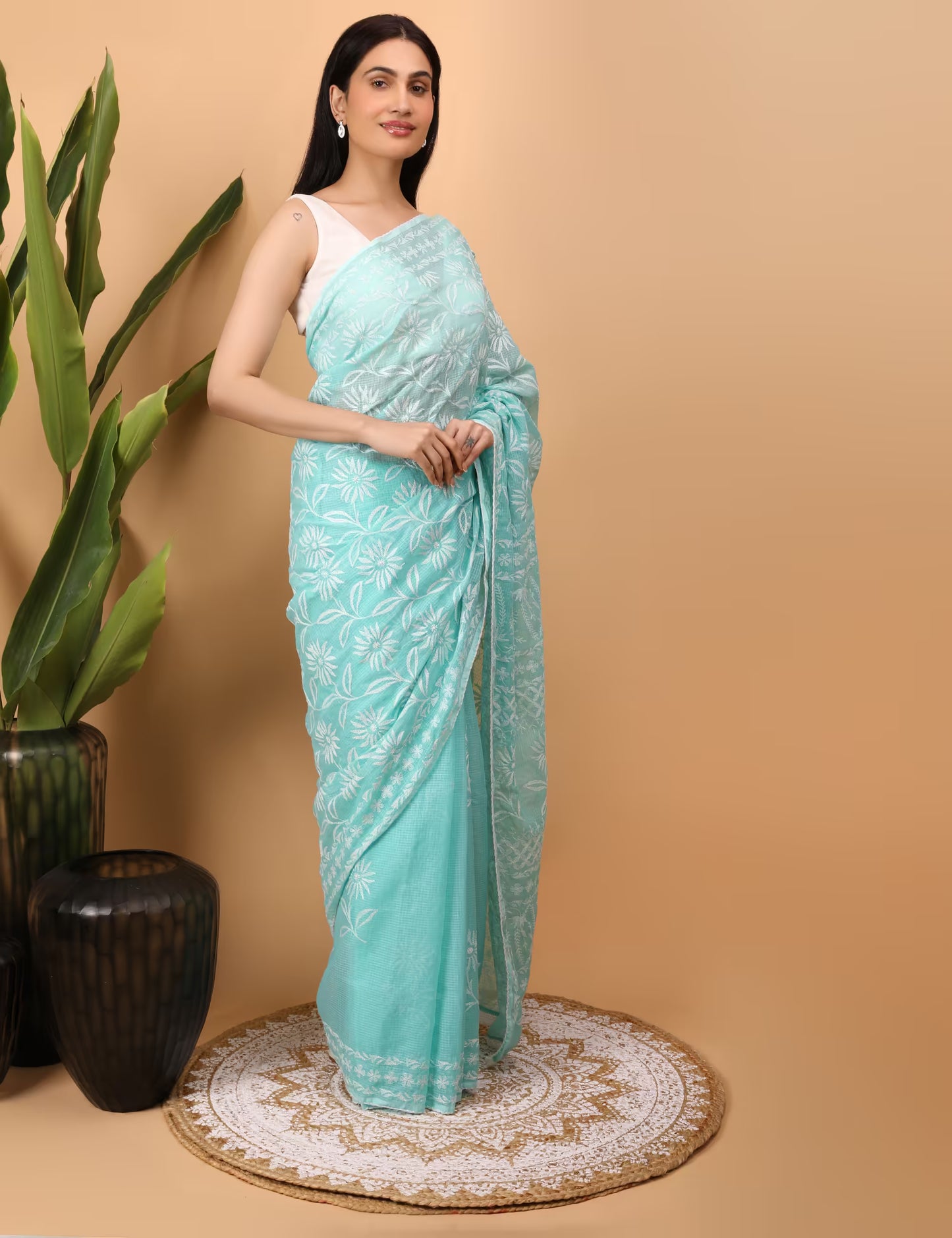Woman wearing a light blue saree with white  Chikankari patterns on a beige background