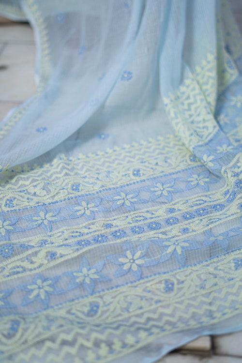 Light blue fabric with floral embroidery on a wooden surface