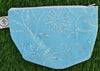 Blue pouch with white floral pattern on grass