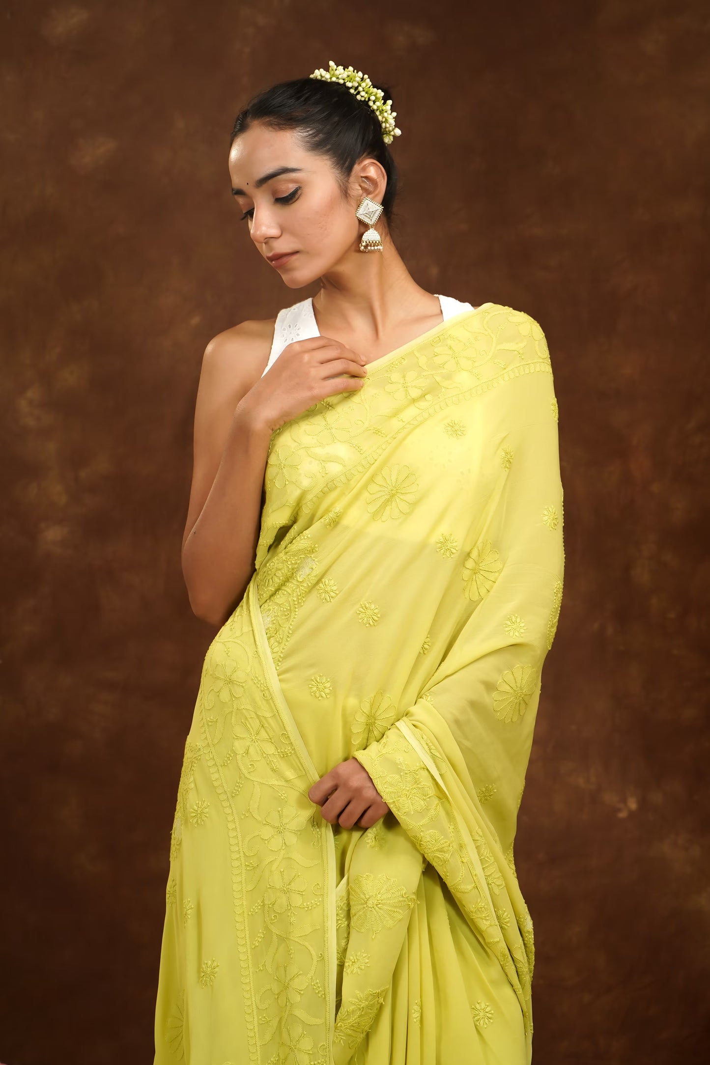 Woman wearing a bright yellow saree against a brown background
