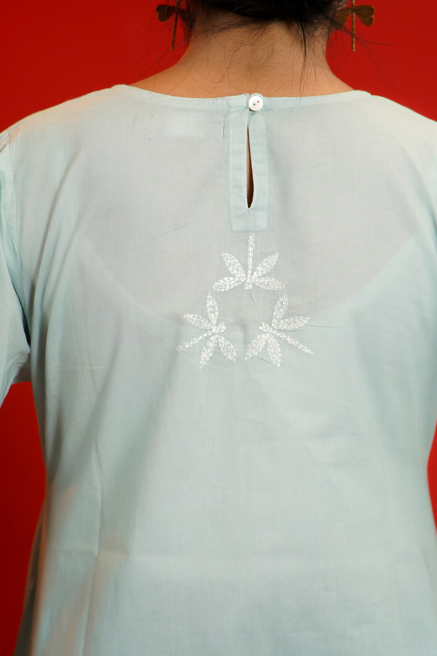Grey top with floral embroidery on a red background