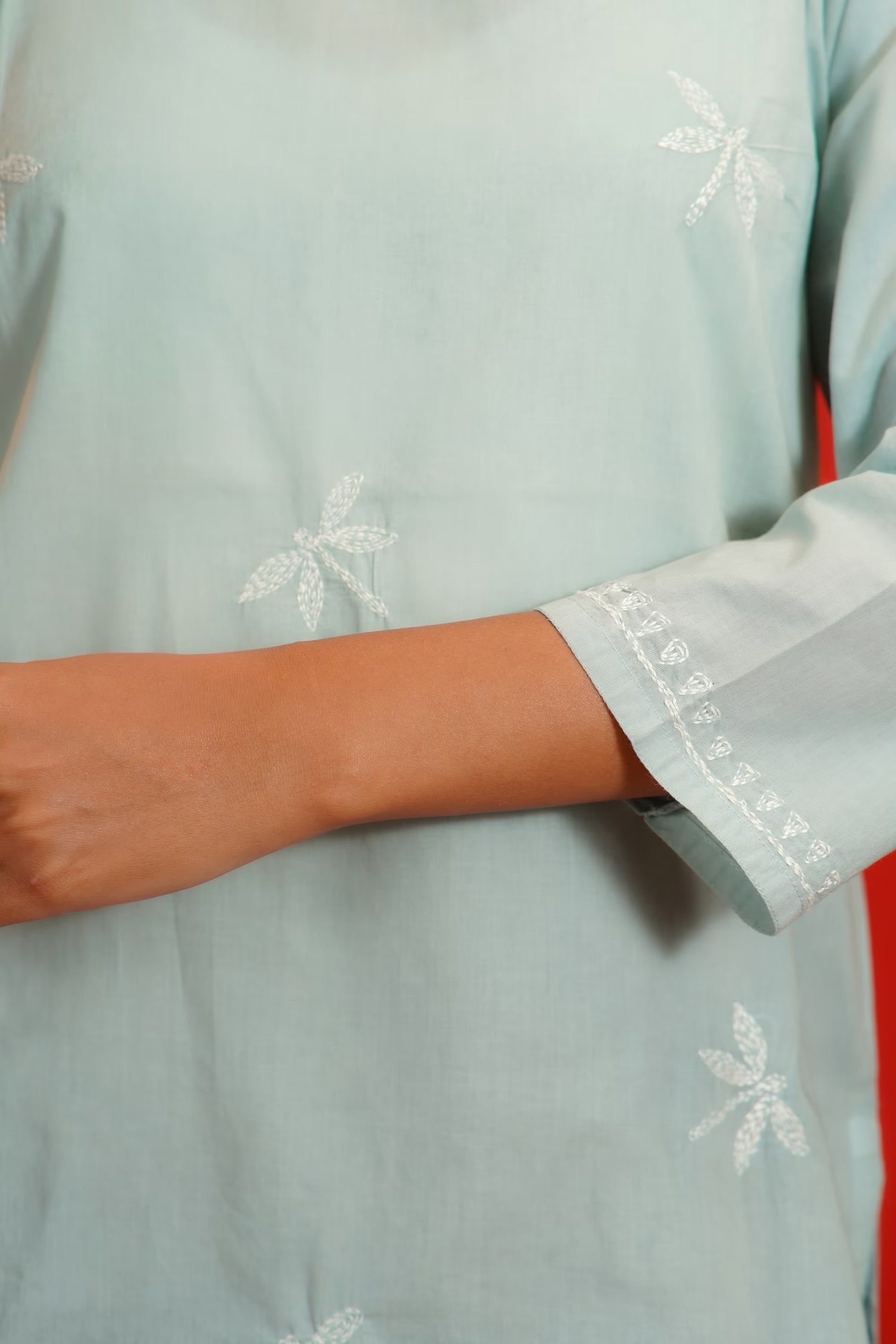 Grey garment with white floral embroidery on a plain background