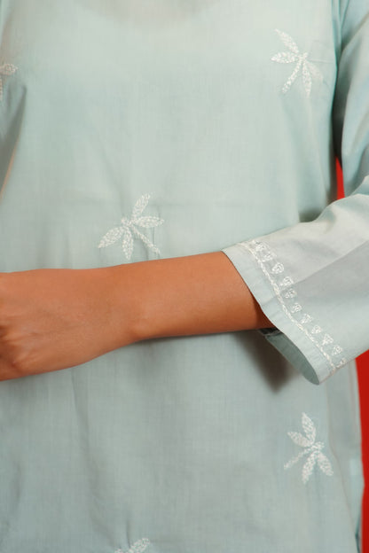 Grey garment with white floral embroidery on a plain background