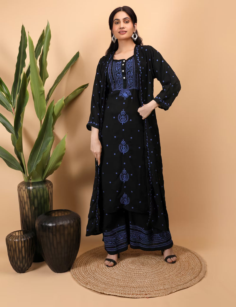 Woman wearing a black embroidered outfit standing next to decorative vases on a beige background