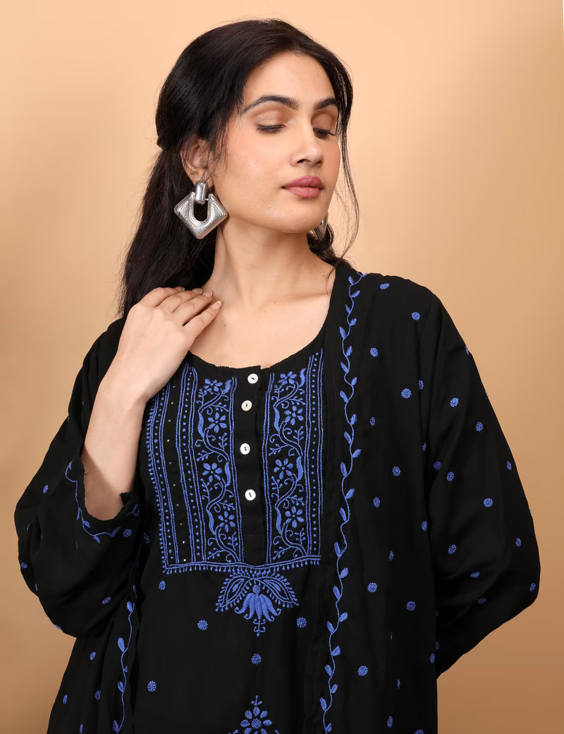 Woman wearing a black and blue embroidered top against a beige background