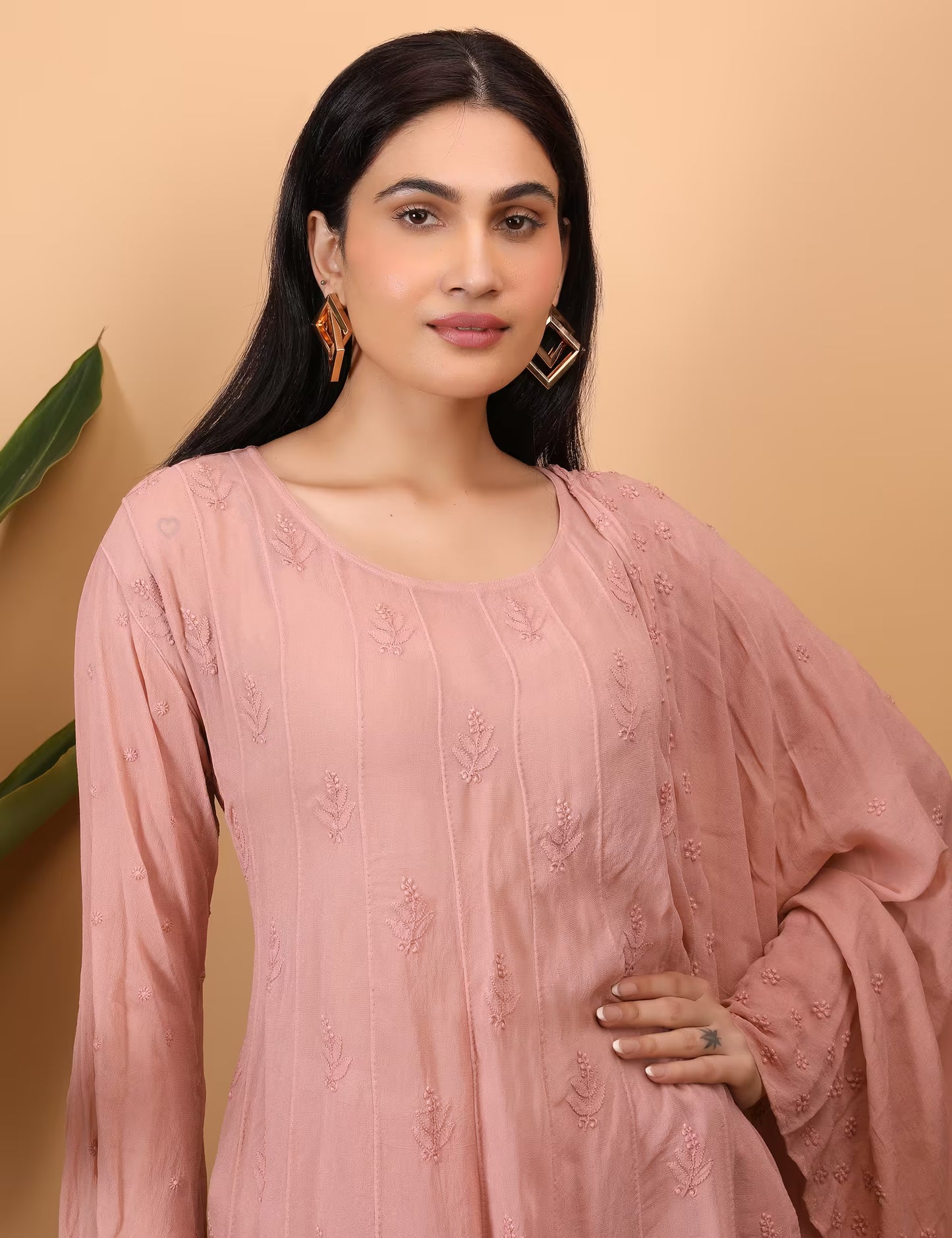 Woman wearing a peach embroidered outfit against a beige background