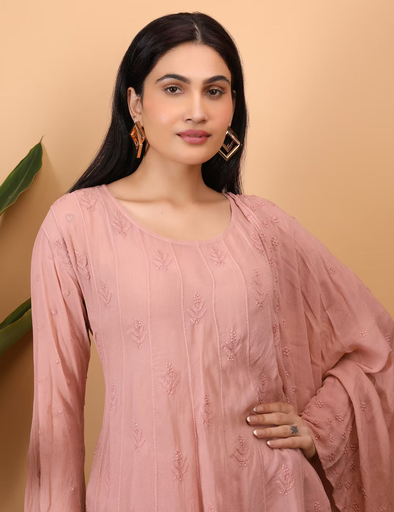 Woman wearing a peach embroidered outfit against a beige background