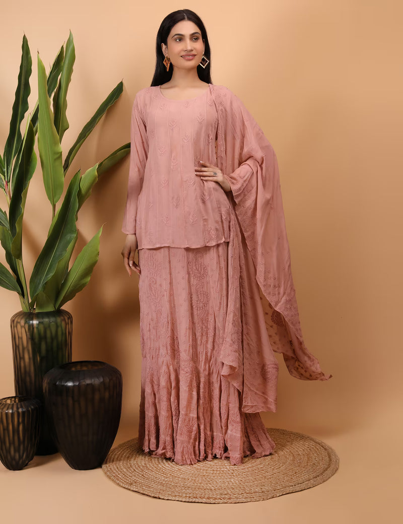 Woman wearing a peach traditional outfit with a plant and vases on a beige background.
