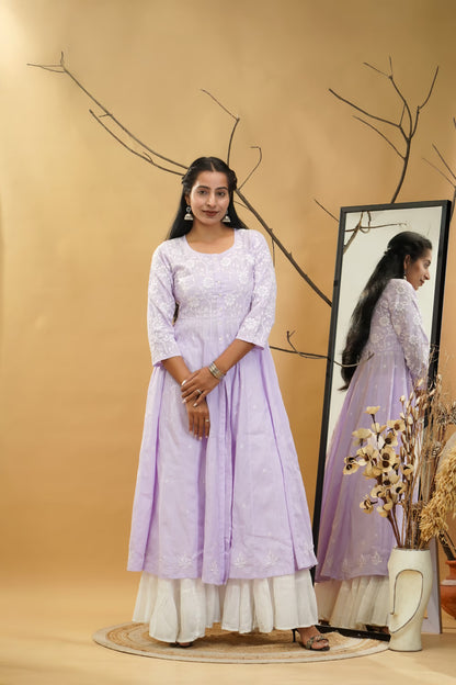 Woman in a light purple dress standing next to a mirror on a beige background