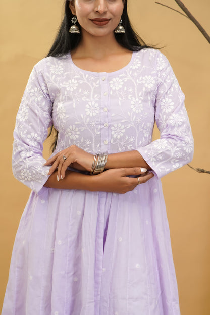 Woman wearing a light purple dress with white floral patterns against a beige background