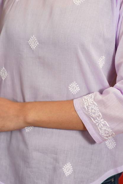 Lavender garment with white floral embroidery on a plain background