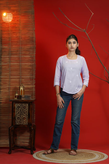 Woman standing in a room with a red wall, wooden side table, and decorative plant.