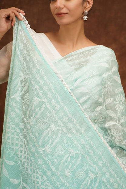 Light blue saree with white patterns held by a person against a brown background