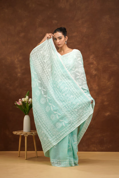Woman in a light blue saree with white patterns against a brown background