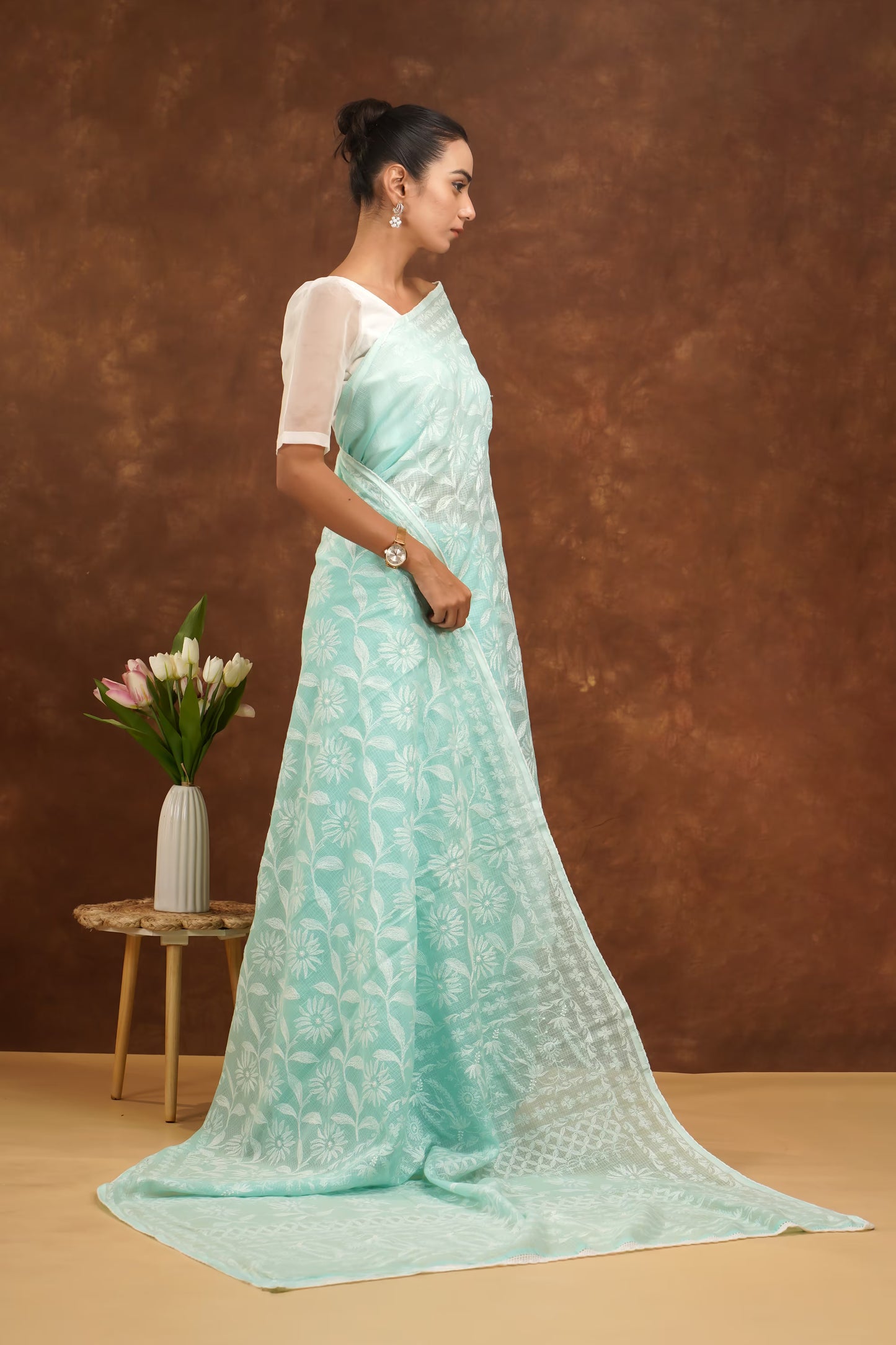 Woman wearing a light blue saree with a brown background