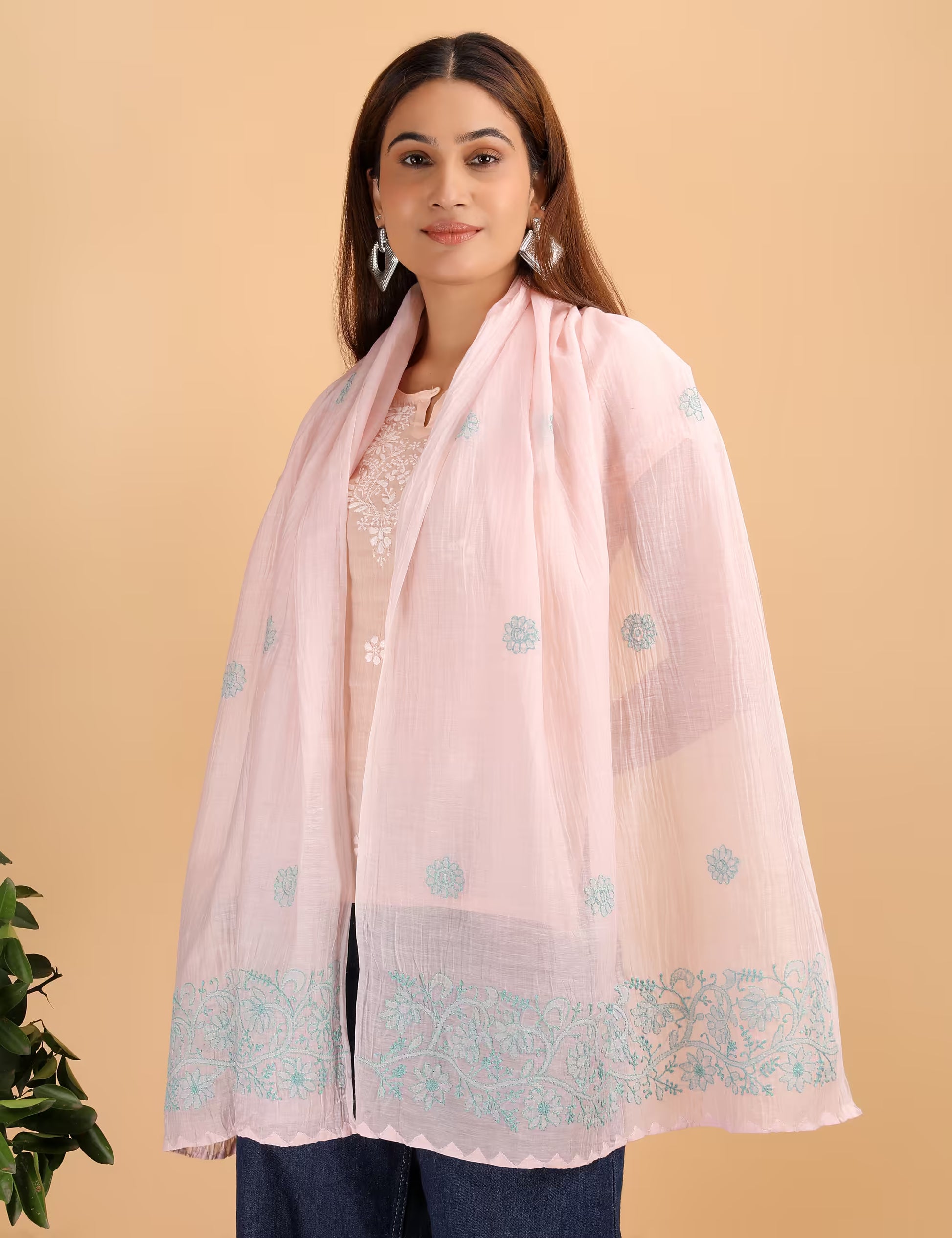 Woman wearing a light pink stole with blue patterns on a beige background