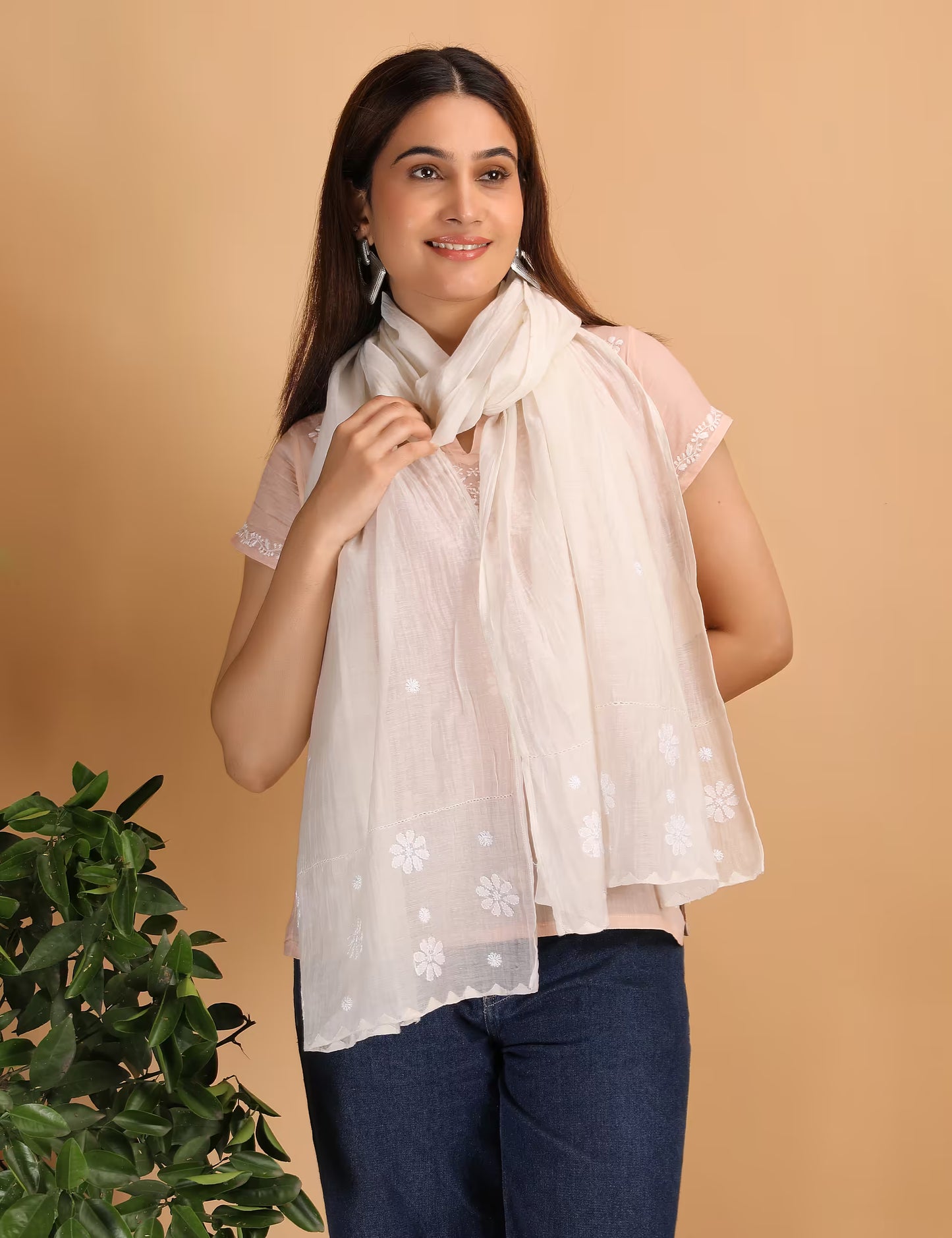 Woman wearing a white scarf with Chikankari patterns against a beige background