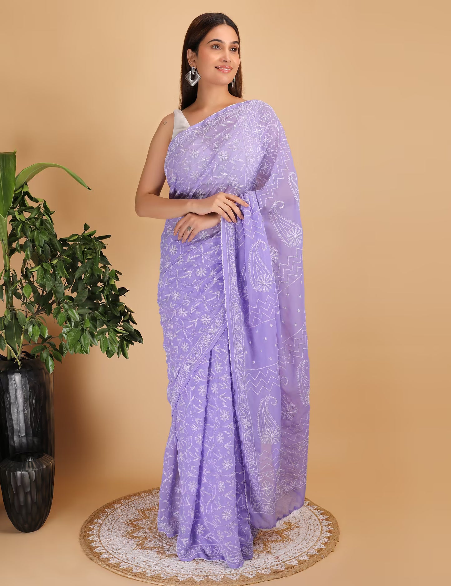 Woman wearing a purple  Chikankari saree with a white  Hand Embroidered pattern on a beige background
