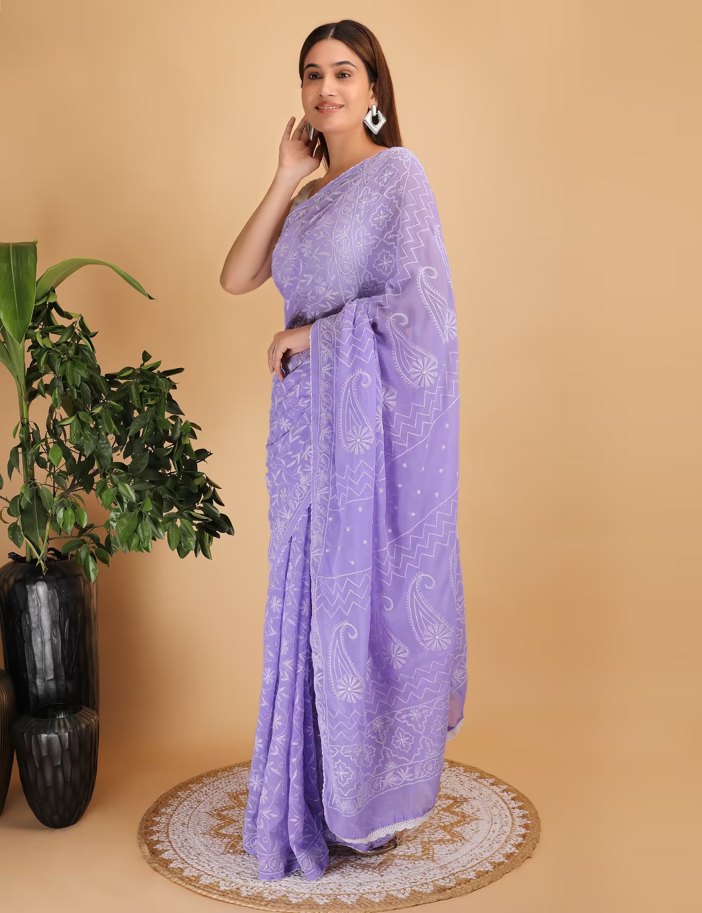 Woman wearing a purple  Chikankari saree with a white pattern on a beige background