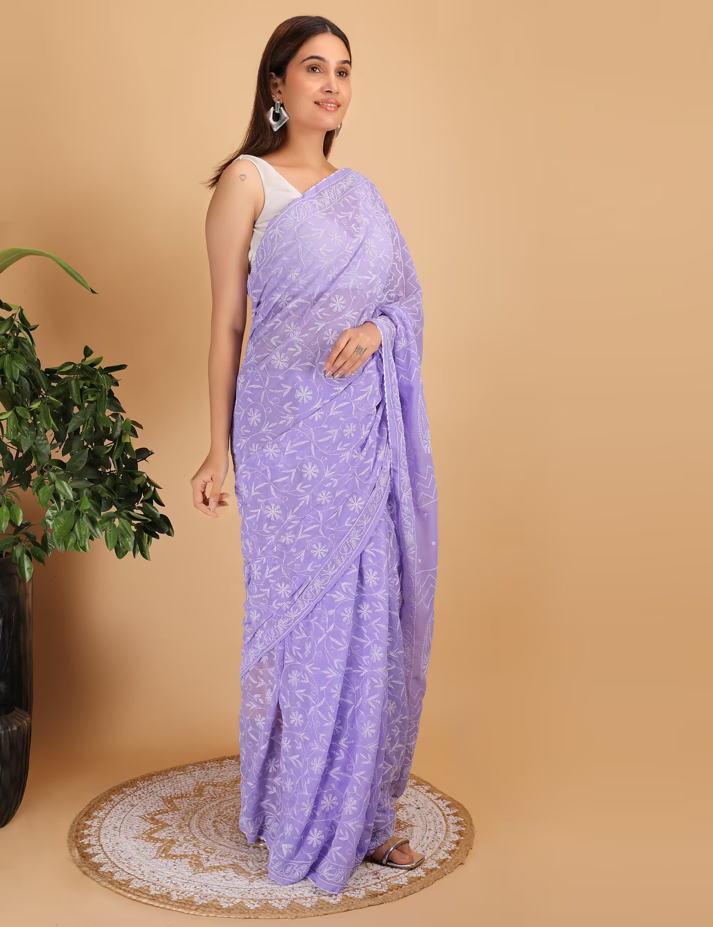 Woman wearing a purple  Chikankari saree with a white background