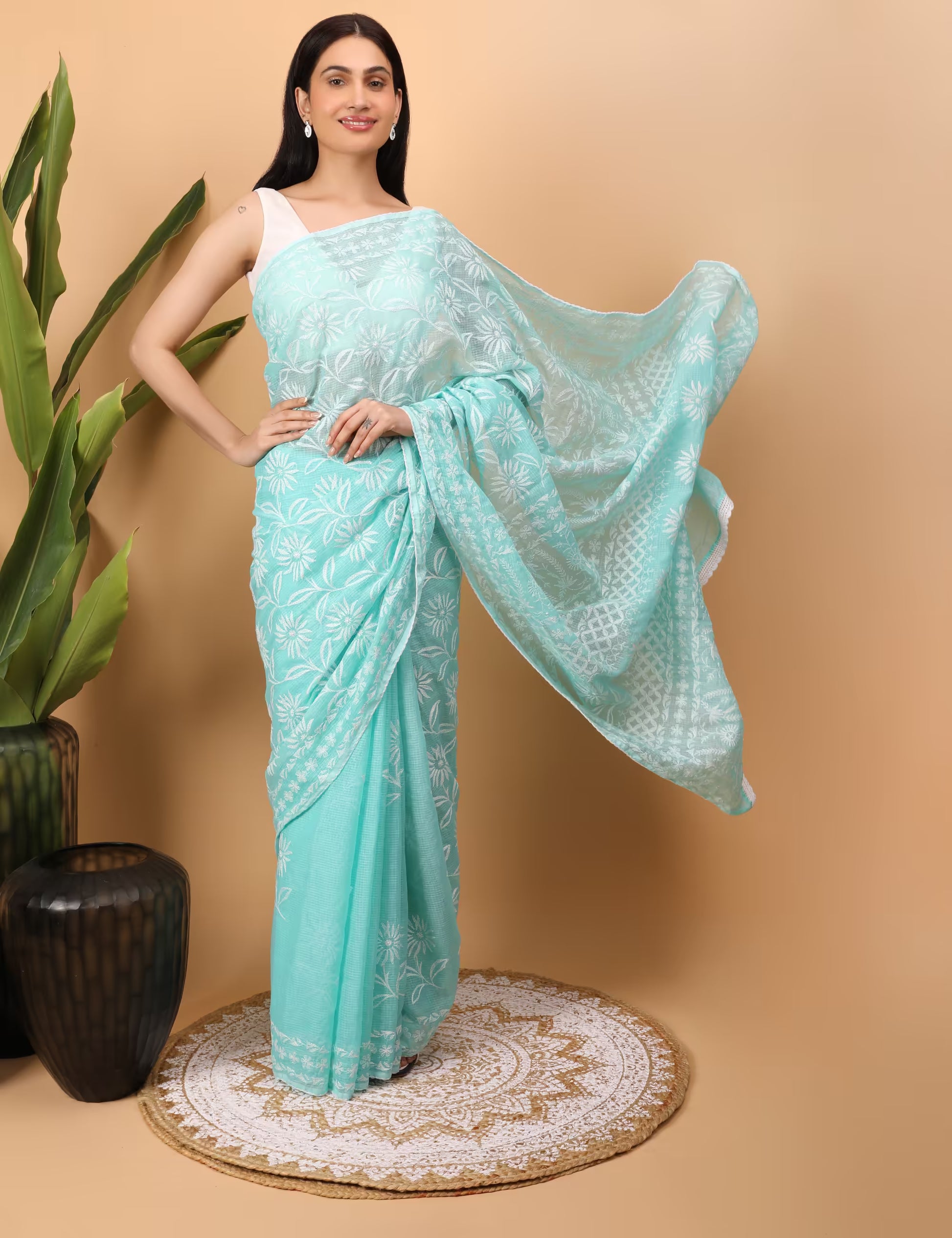 Woman wearing a light blue saree with white Chikankari patterns on a beige background