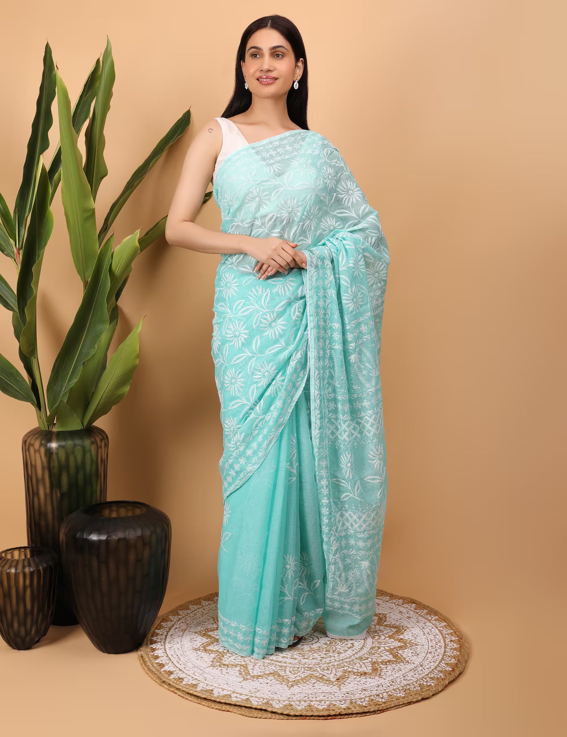 Woman wearing a light blue saree with white Chikankari Pattern  on a beige background