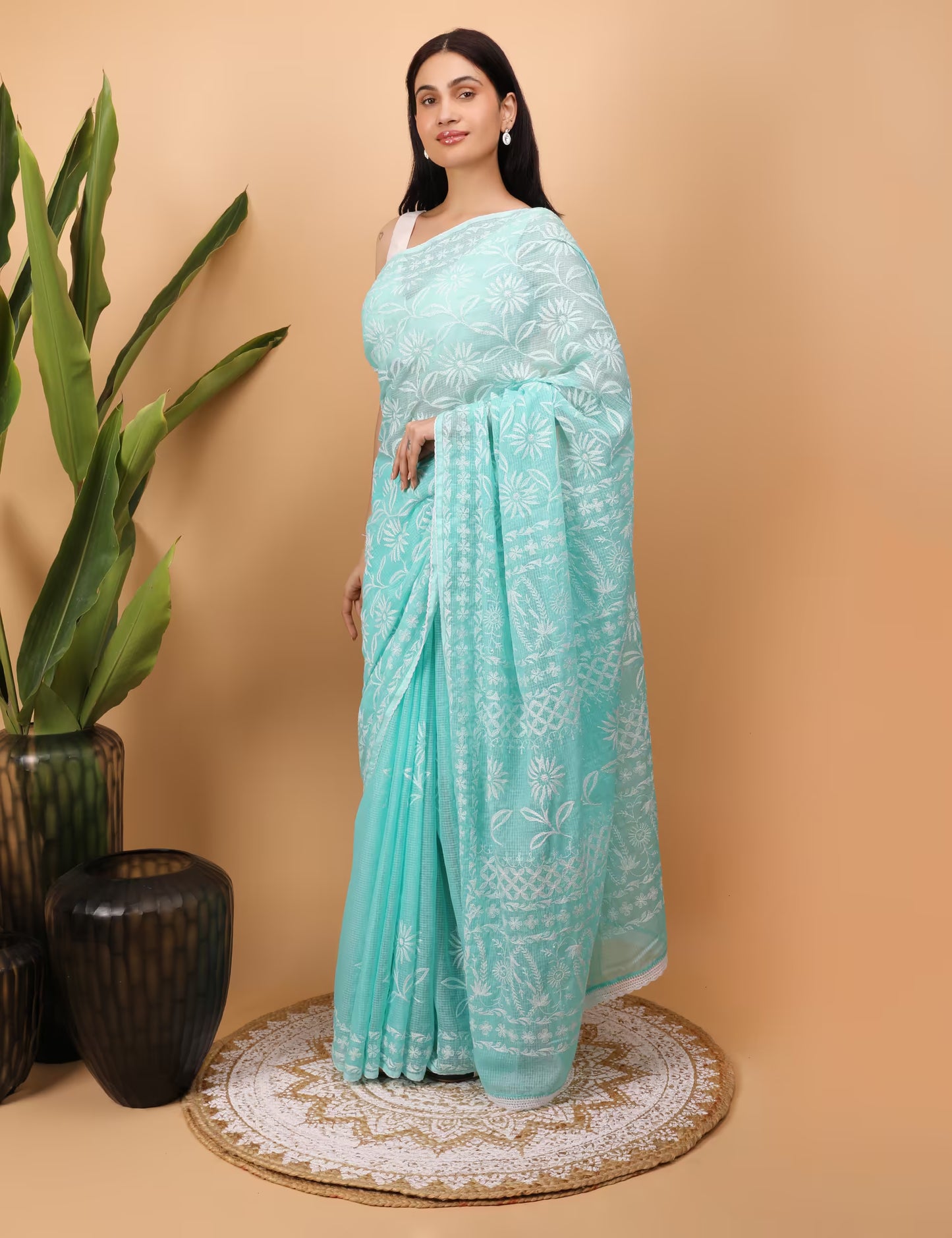 Woman wearing a light blue  Chikankari saree with white  Hand Embroidered patterns on a beige background