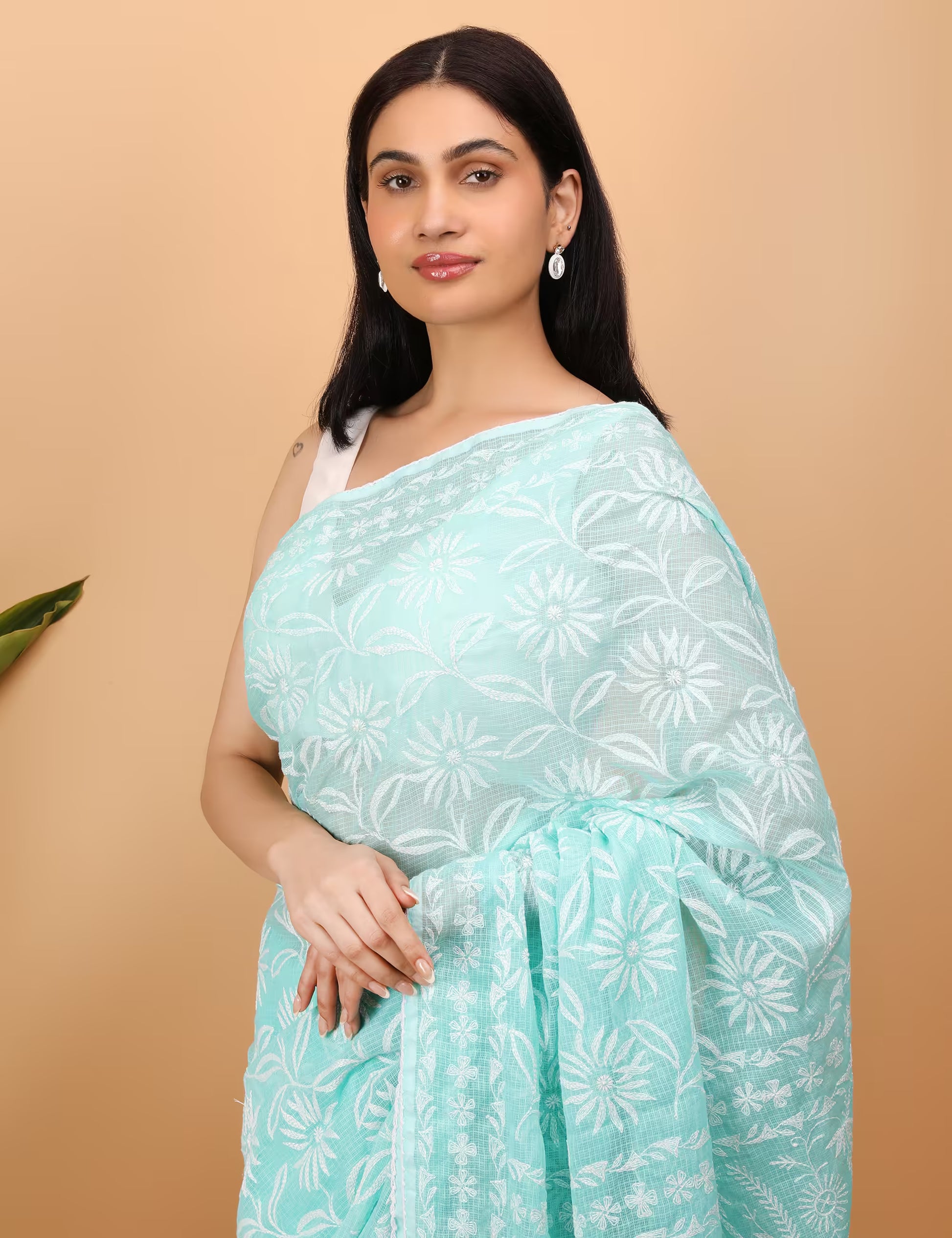 Woman wearing a light blue saree with white Chikankari  patterns on a beige background