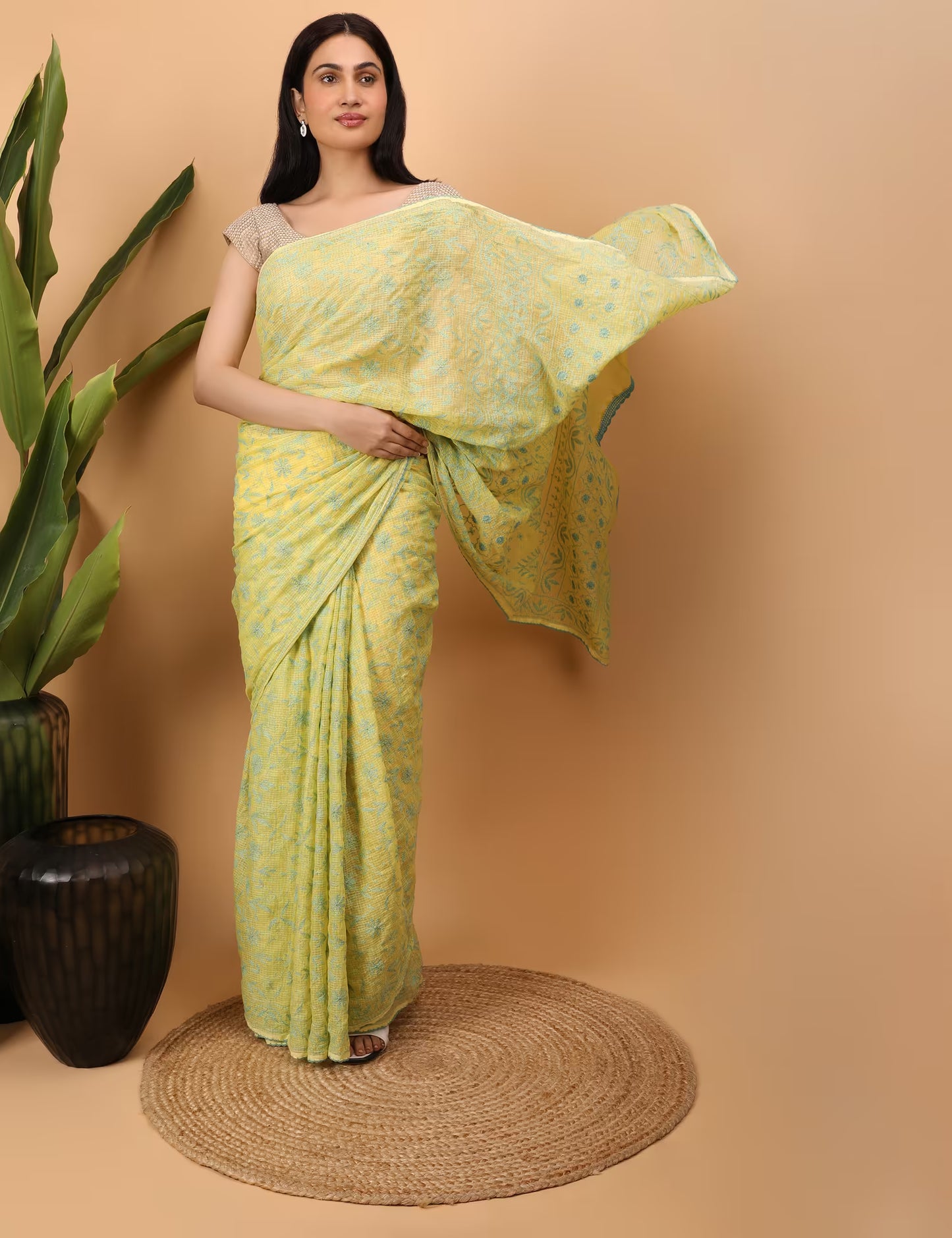 Woman wearing a light green saree with a subtle  Chikankari pattern against a beige background