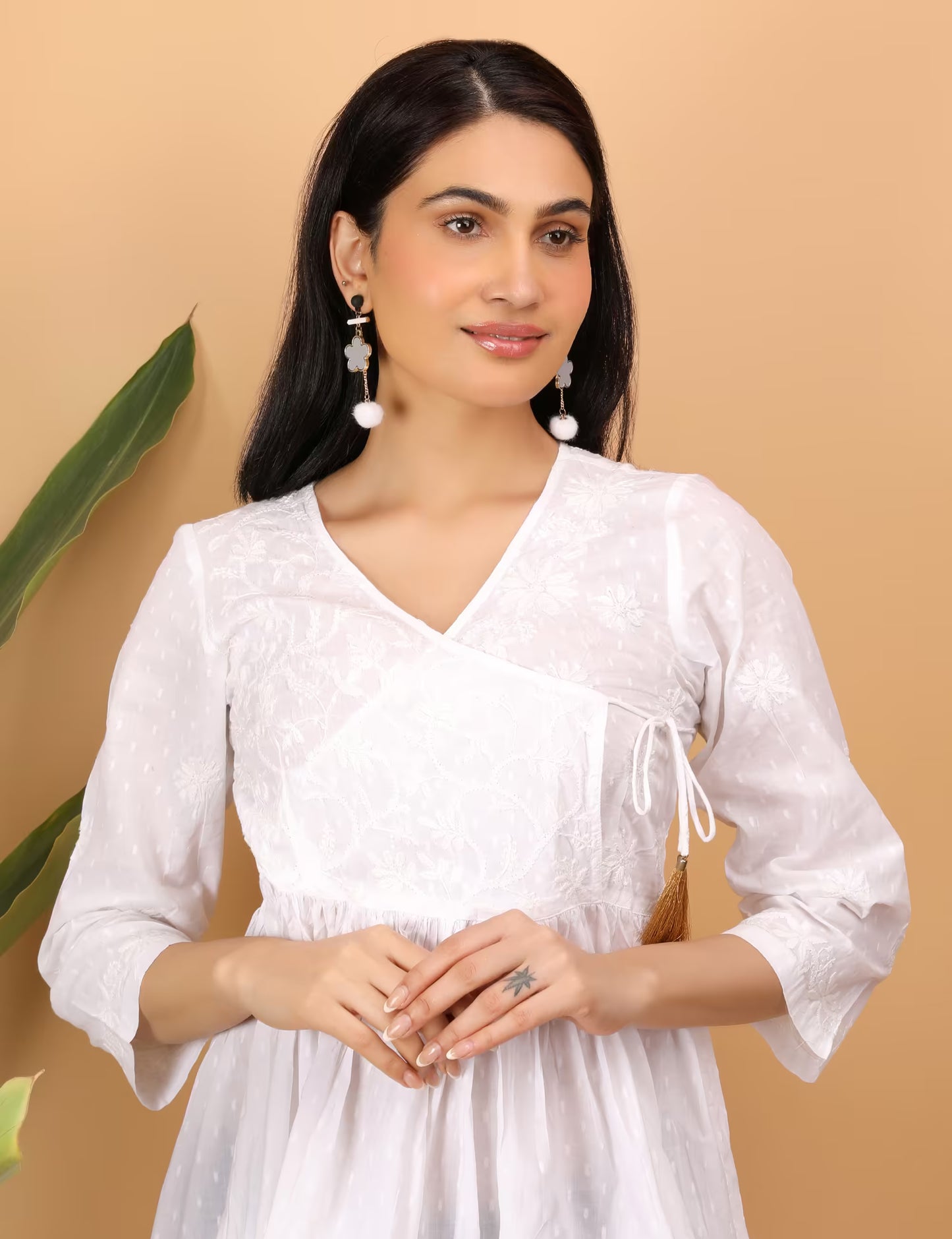 Woman wearing a white chikankari top  with a beige background