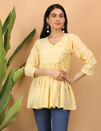 Woman wearing a yellow  Chikankari top  with a beige background