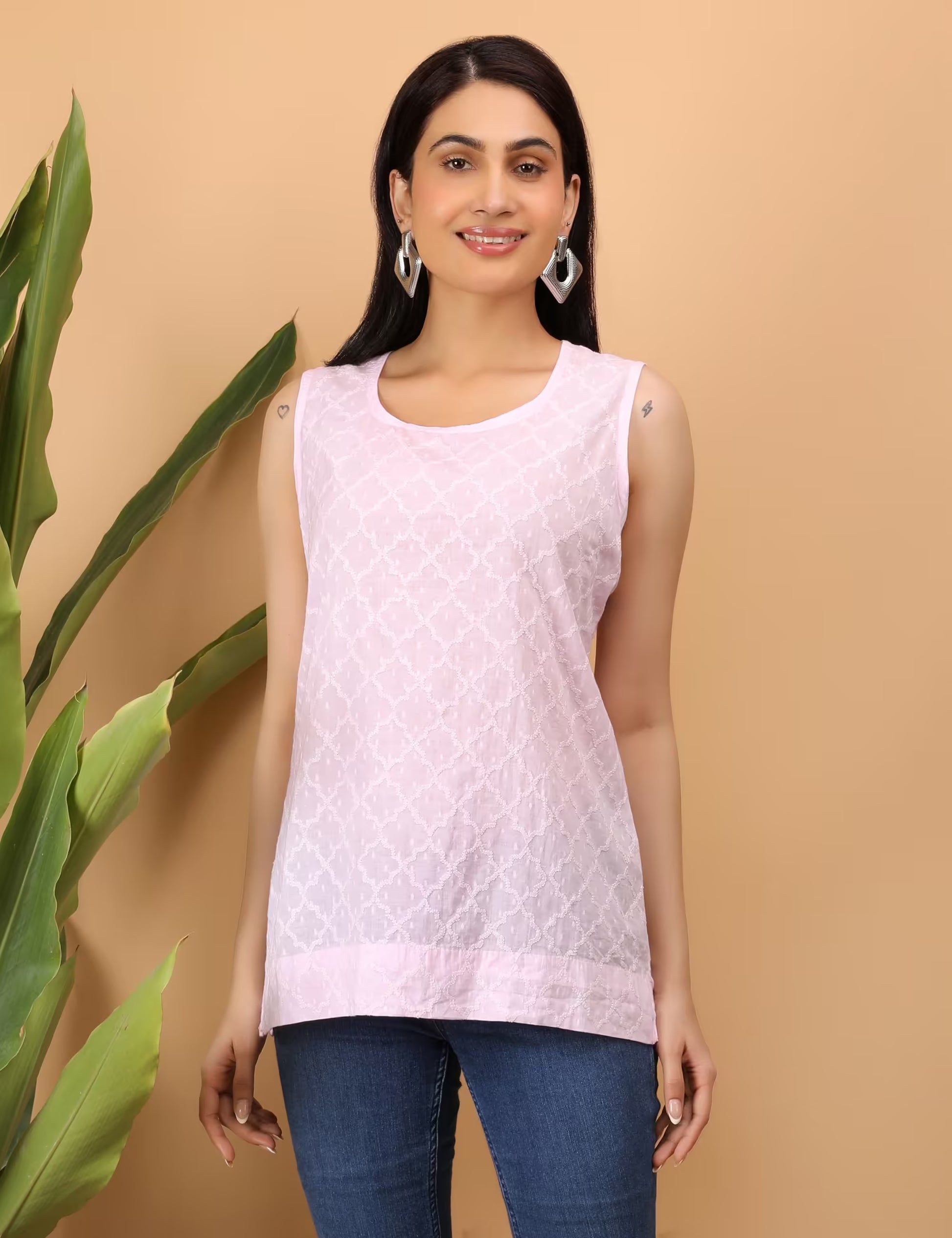 Woman wearing a light pink Chikankari sleeveless top with a beige background