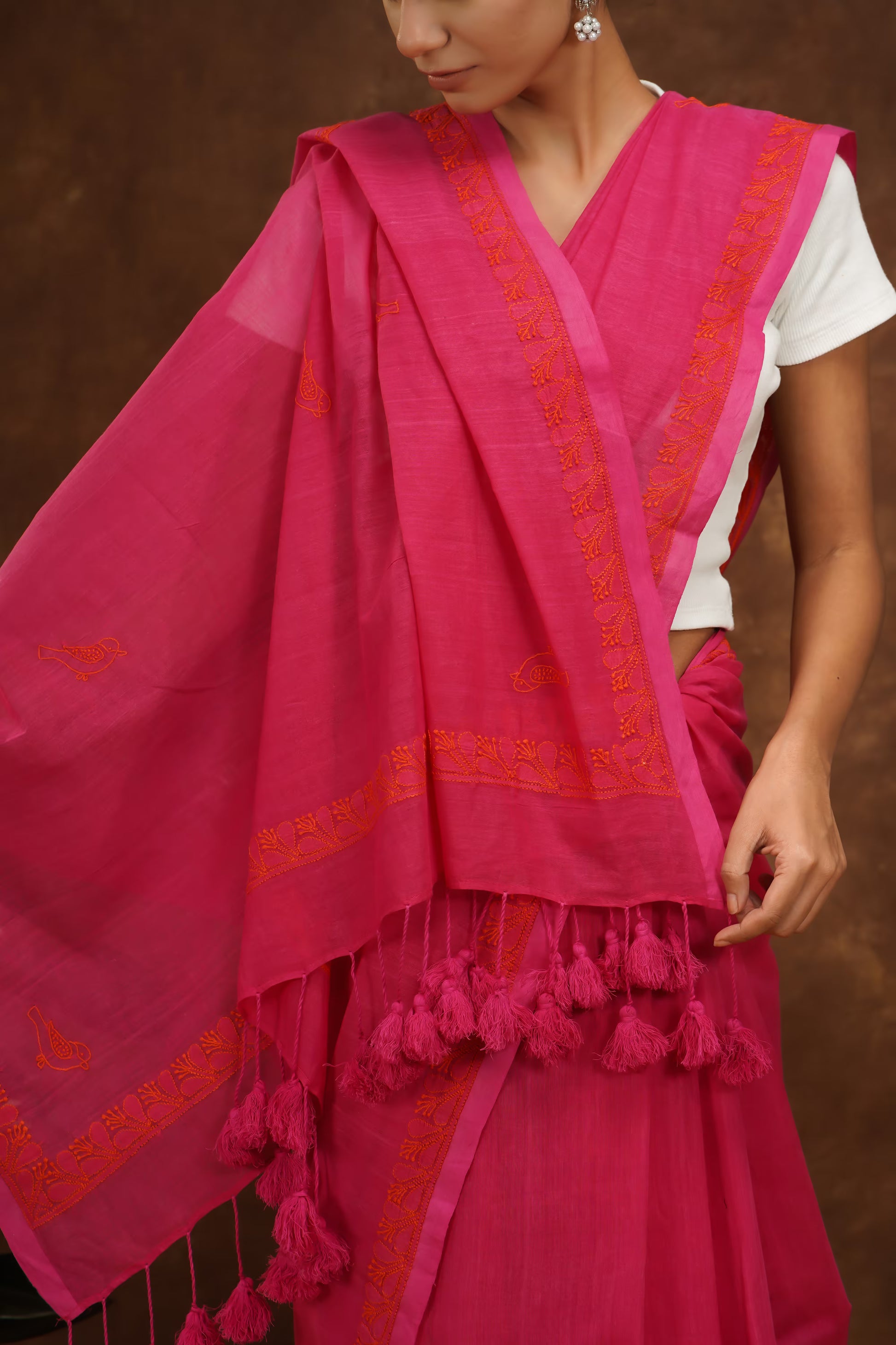Woman wearing a megenta traditional outfit with intricate designs on a brown background