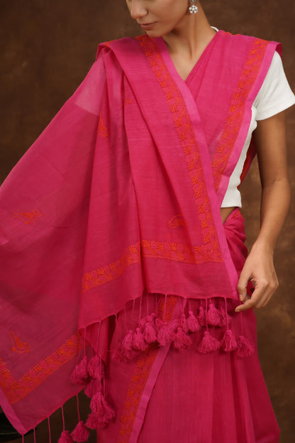 Woman wearing a megenta traditional outfit with intricate designs on a brown background