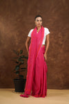 Woman wearing a megenta saree with a white blouse against a brown background