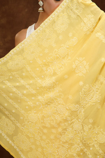 Yellow saree with intricate white patterns held by a person against a dark background