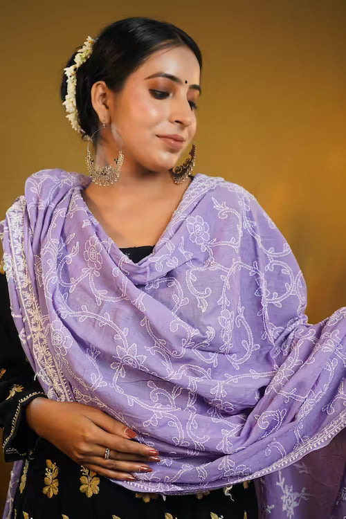 Woman wearing a purple dupatta with white  Chikankari patterns against a warm-toned background